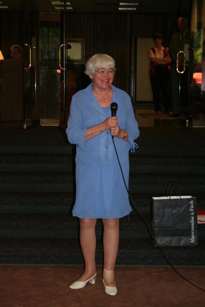 Peggy Cover stands holding a microphone