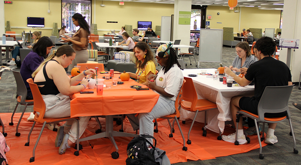 Students painting pumpkins during a Halloween event in the Learning Commons.