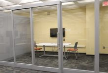 3rd floor group study space featuring a table with chairs and a monitor surrounded by glass walls