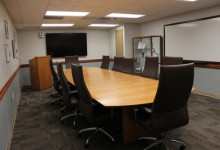 2nd floor group study space featuring a table with chairs to seat 12 and a monitor, with a closing door