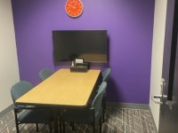 interview room with a desk, four chairs and a display